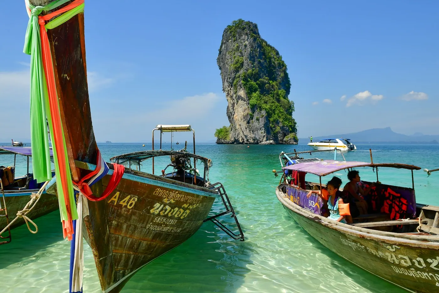 The ribboned bows of traditional longtail boats over clear turquoise water