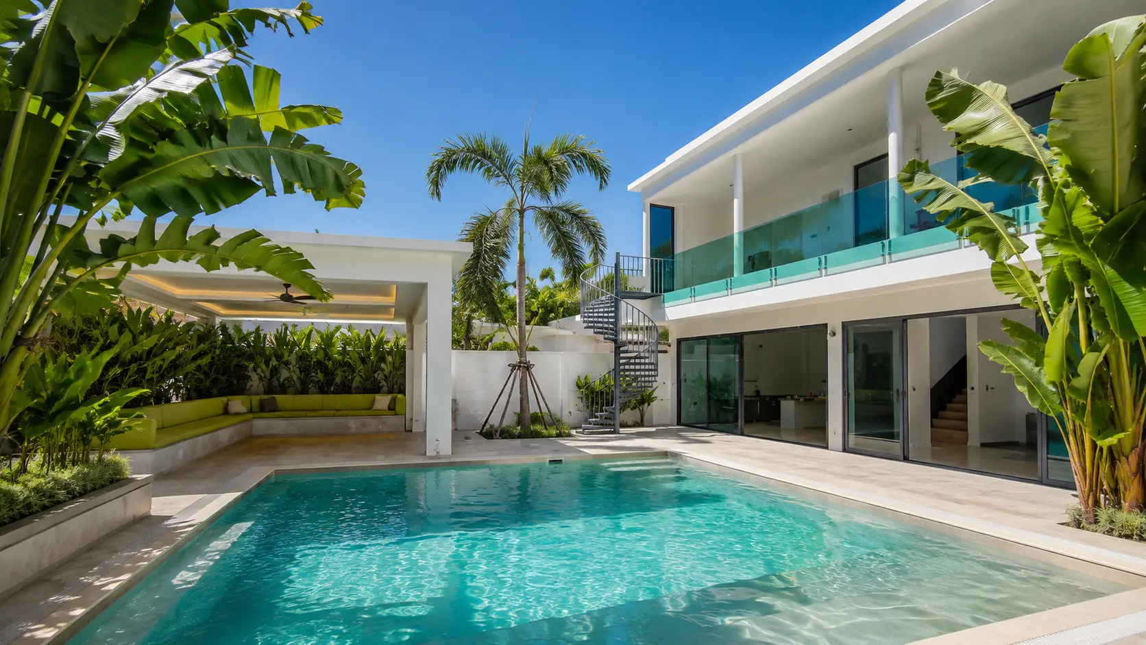 Sun House Rawai's white facade and swimming pool framed by tropical planting
